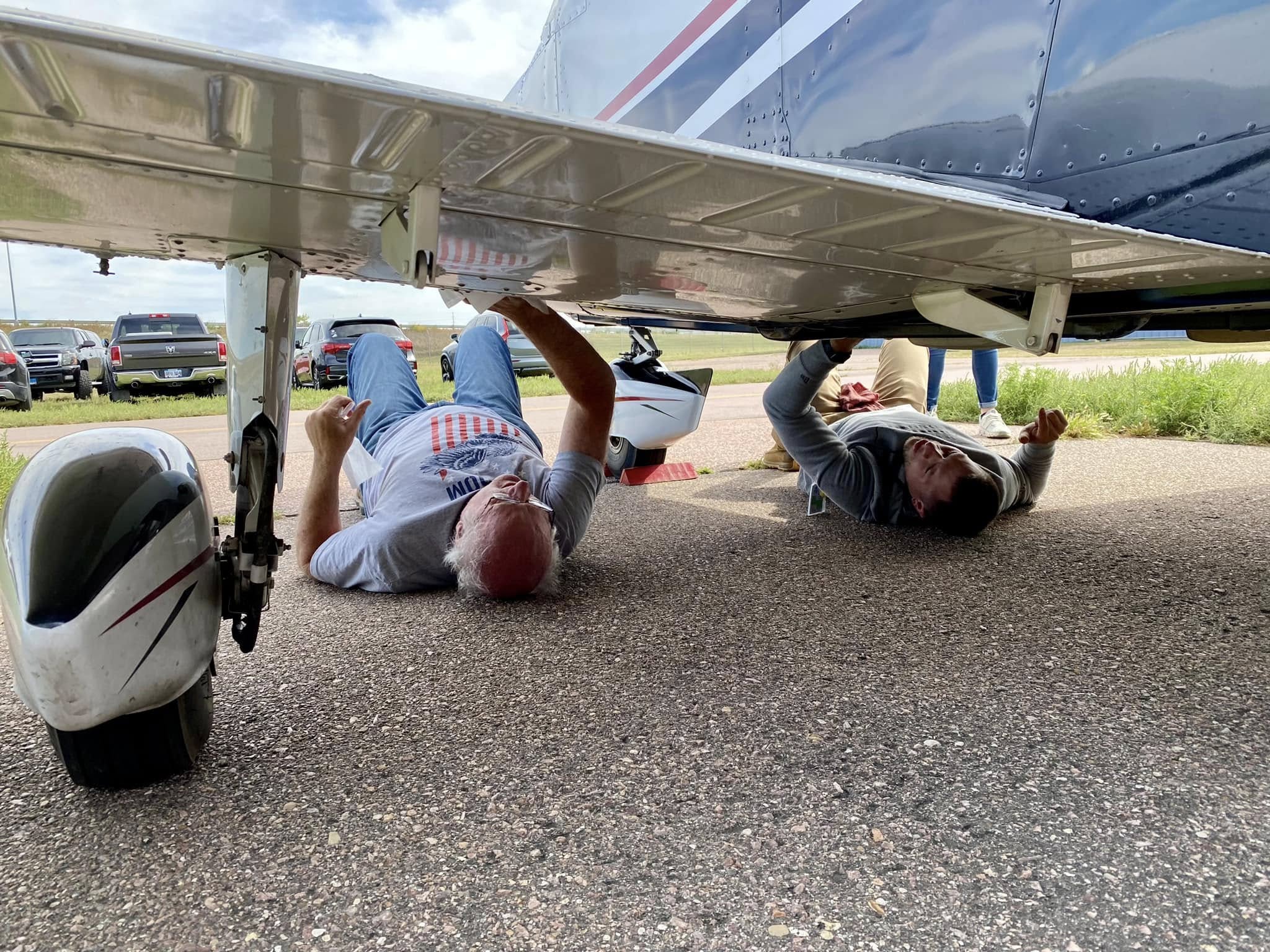 Club members working under an airplane wing during a maintenance day
