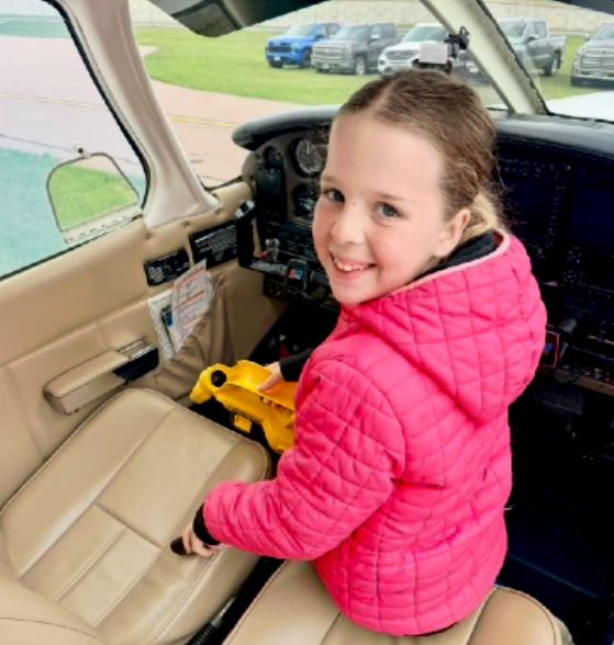 Young passenger smiling in the front seat of a club airplane